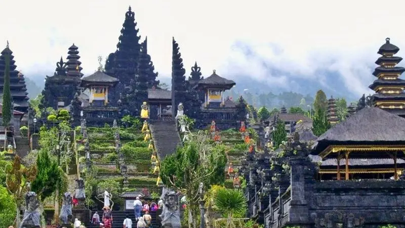 Visitors walking through the courtyards of Besakih Temple with scenic views of Mount Agung in the background.